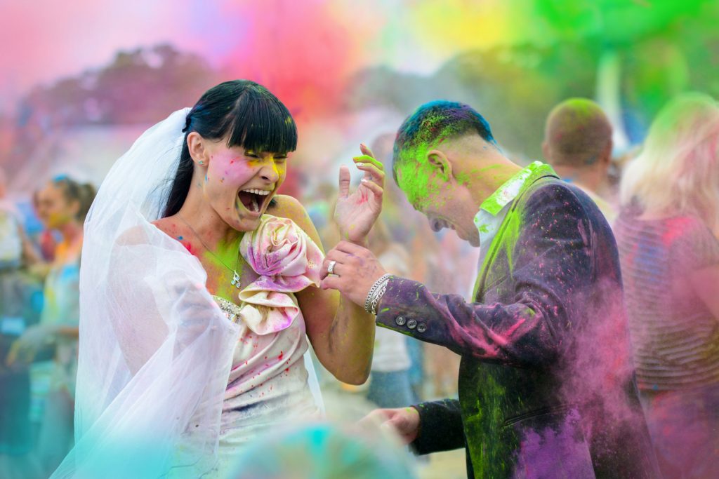 Young cheerful couple at Holi paint party
