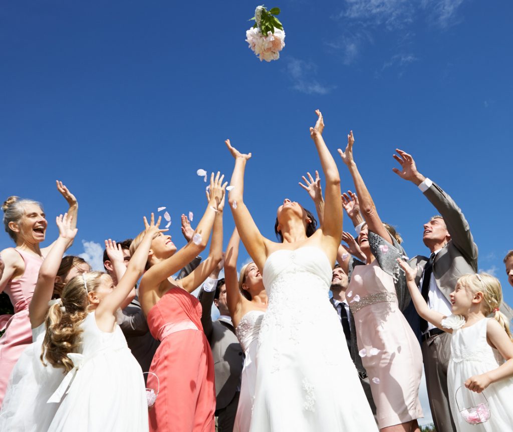 Bride Throwing Bouquet Outdoors For Guests To Catch