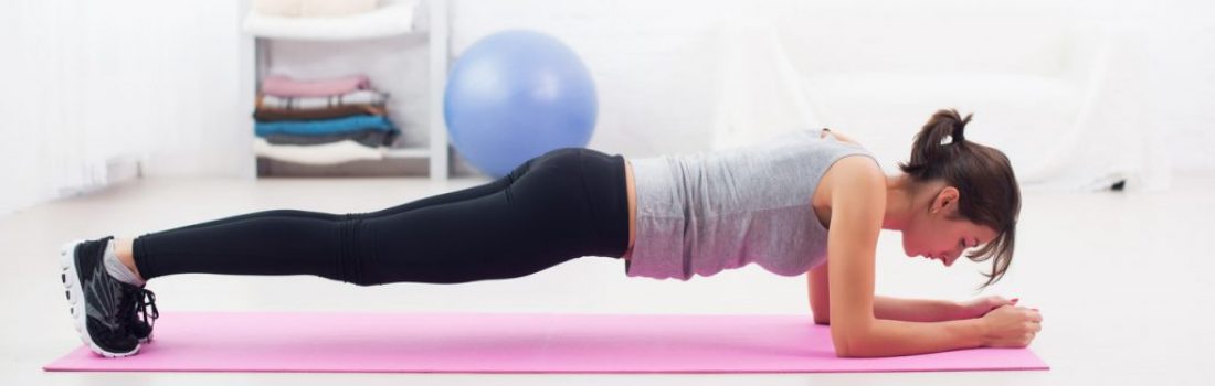 Fit girl in plank position on mat at home in the living room exercise for back spine and posture Concept pilates fitness sport